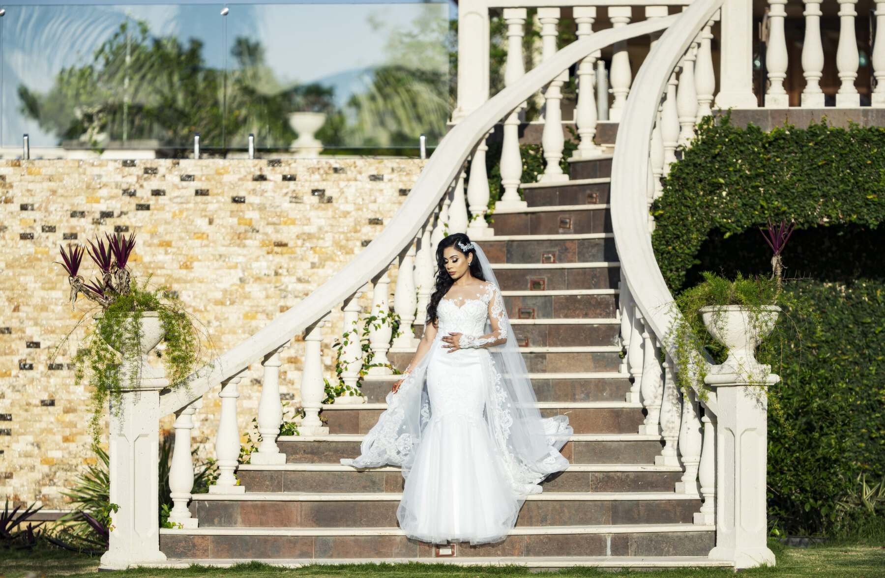 Bride in a lace gown standing on a sweeping outdoor staircase