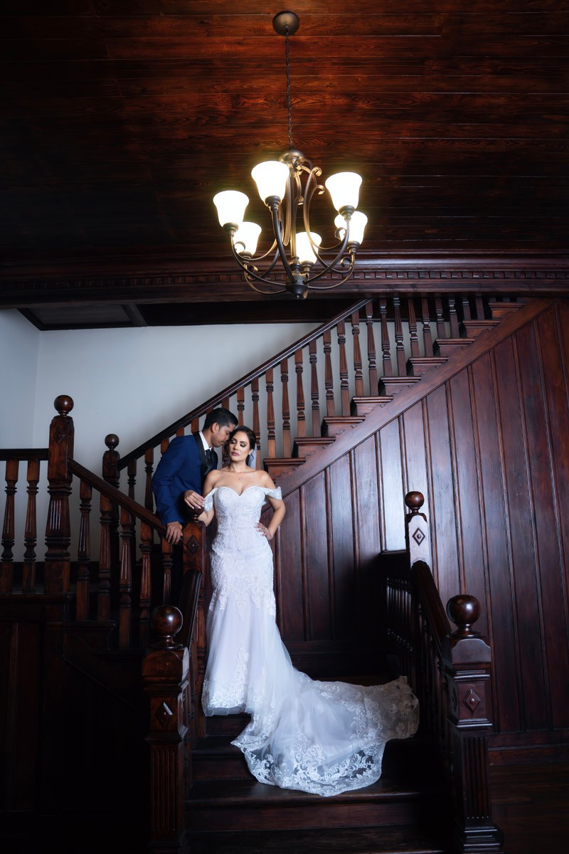 Newlyweds posed together on a grand wooden staircase